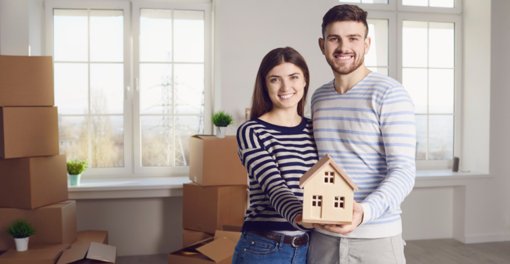 couple holding a miniature house model; steps to selling a house by owner